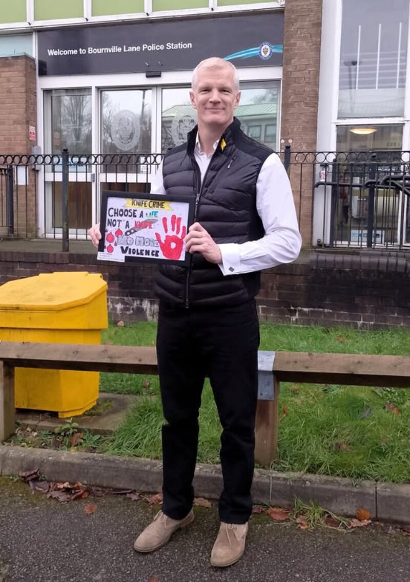 Al standing outside the school with the winning design